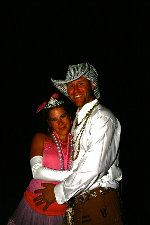 man in a white hat hugging a woman in a pink dress