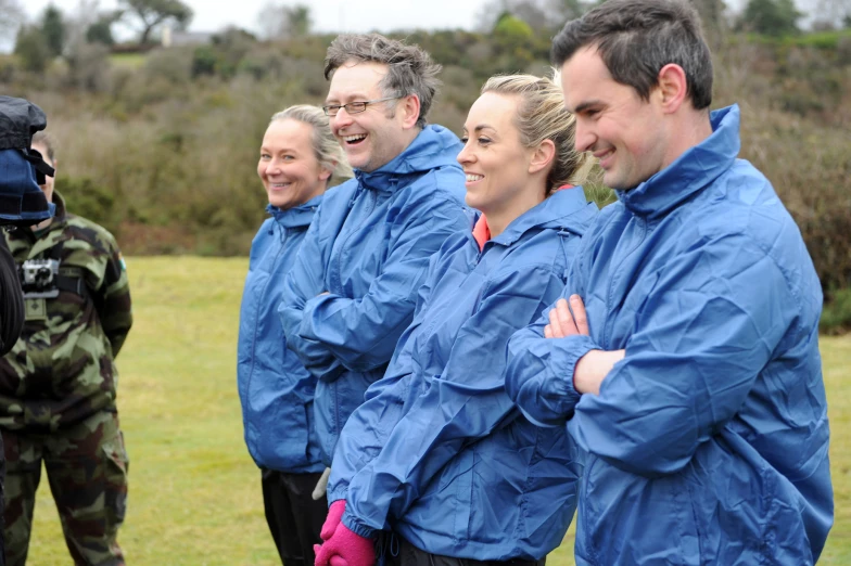 a group of people wearing blue jackets are posing for a picture