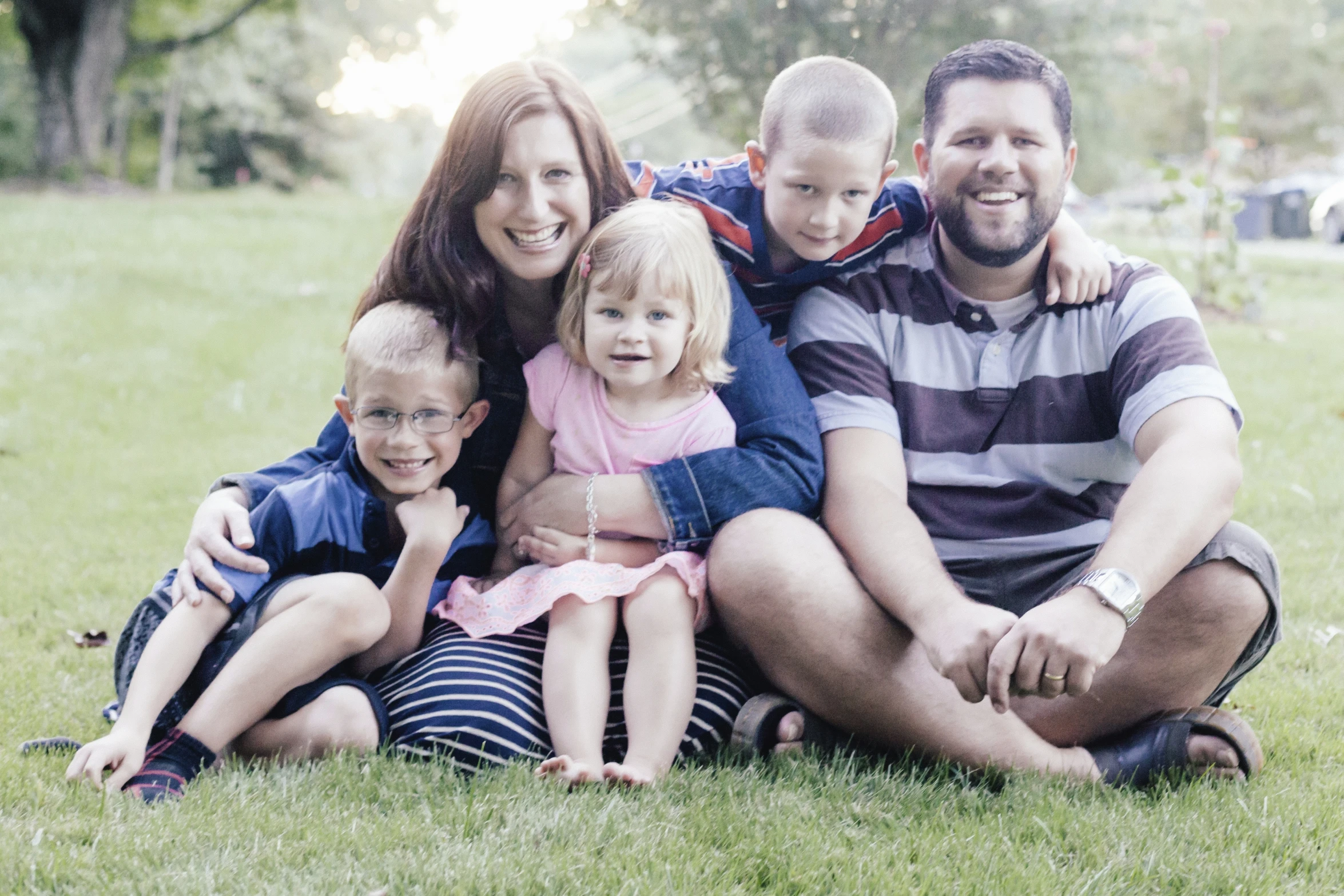 a family sits together in the park in their family pos