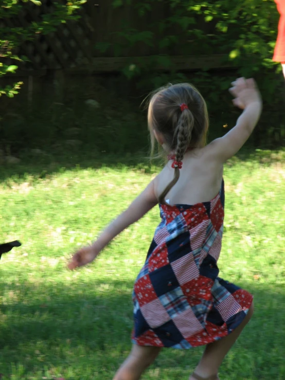 a little girl is throwing a frisbee in a yard