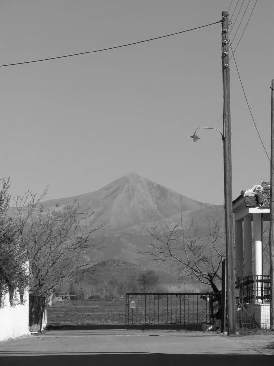 a tall mountain sits in the background with a fence and telephone pole to the left