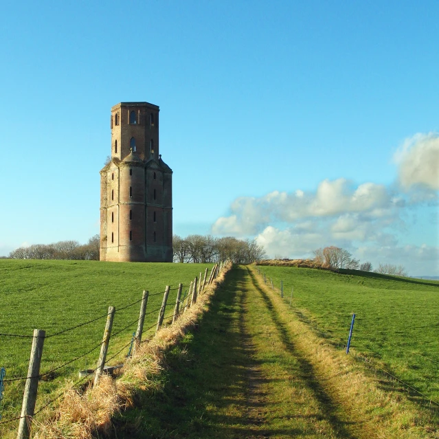 a large brick tower on top of a green field