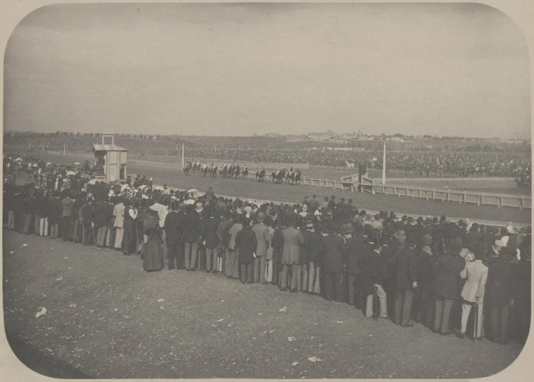 a group of people gathered next to a horse race track
