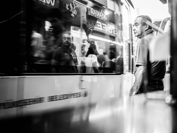 a man waits on a subway platform as a train moves past him