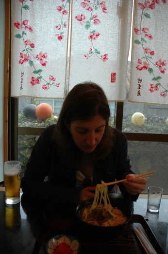 a woman eats food with chopsticks at a restaurant