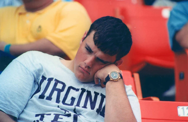 a boy sitting in the stands with his hands resting against his chin