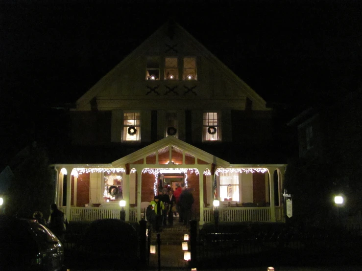 several people stand at the front entrance of a house at night