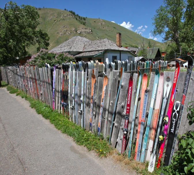 a lot of skis are hanging on a fence