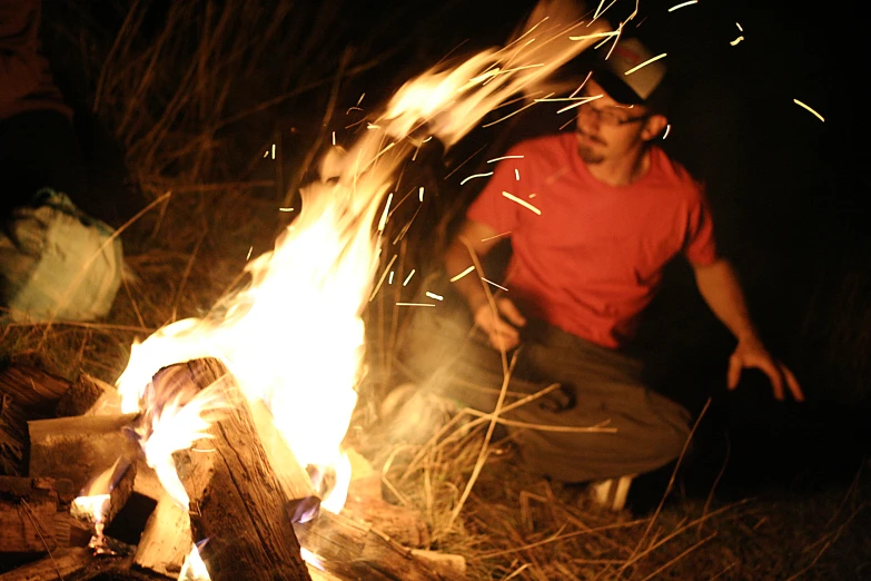 a man kneeling by a fire in the woods