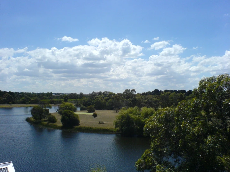 trees and bushes surround the lake with clouds above