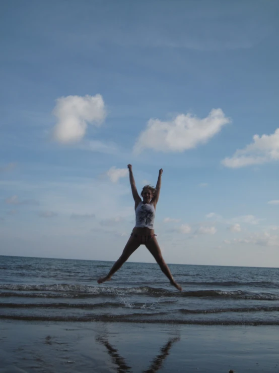 a woman jumps in the air while standing on a beach