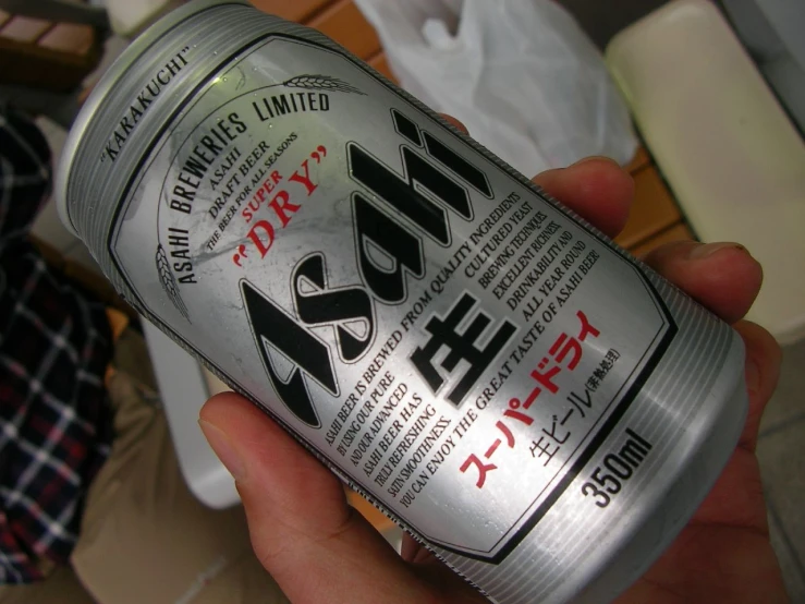 someone holding up an aluminum can with japanese writing
