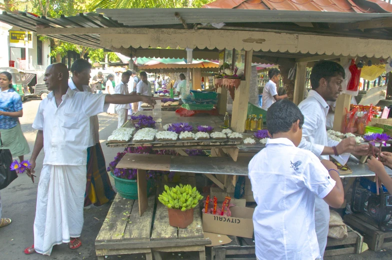 a man selling flowers to the vendors in a street