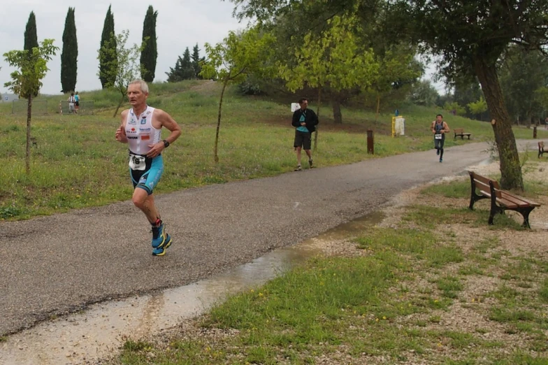 an older man running down a park road