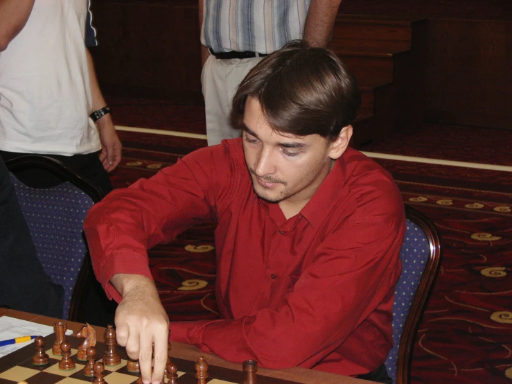 a man in red playing chess at a table