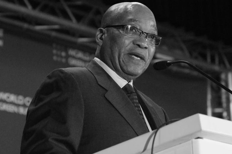 an older man in glasses speaks at a podium