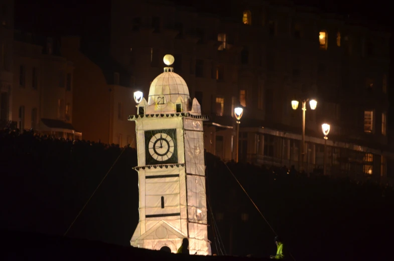 a lit up clock tower next to a building