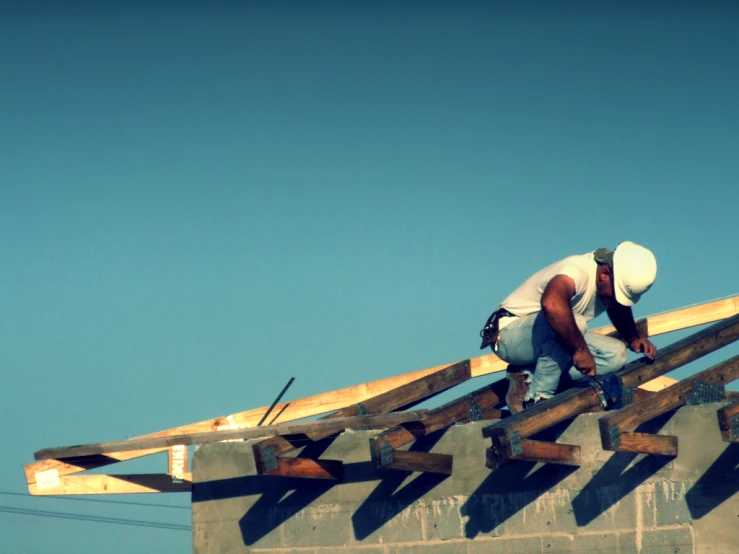 a construction worker fixing wood rafters on top of a wooden structure