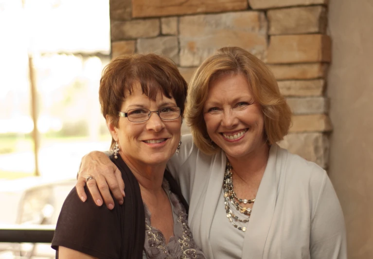 two woman stand next to each other and pose for the camera