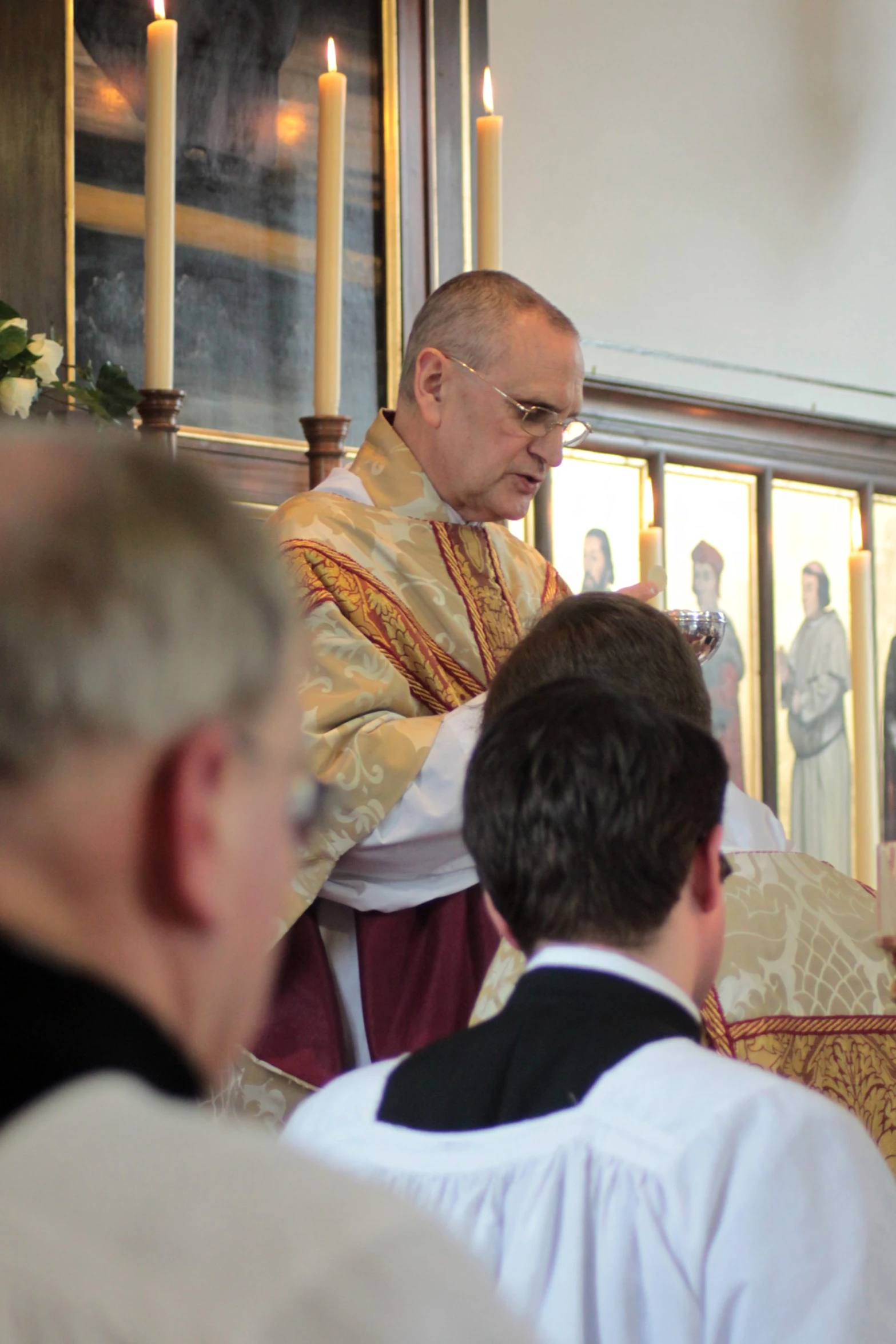 a priest sitting in front of a altar with candles