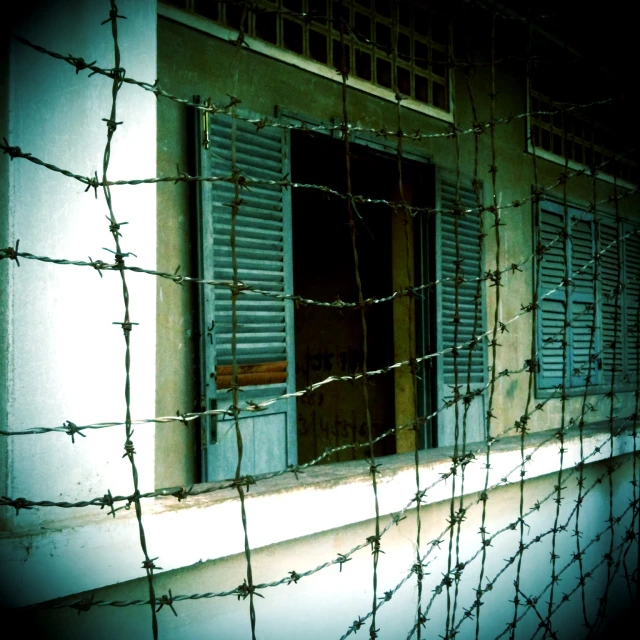 a window in an old building with a chain link fence