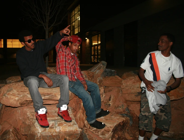 a group of young men sit on some rocks