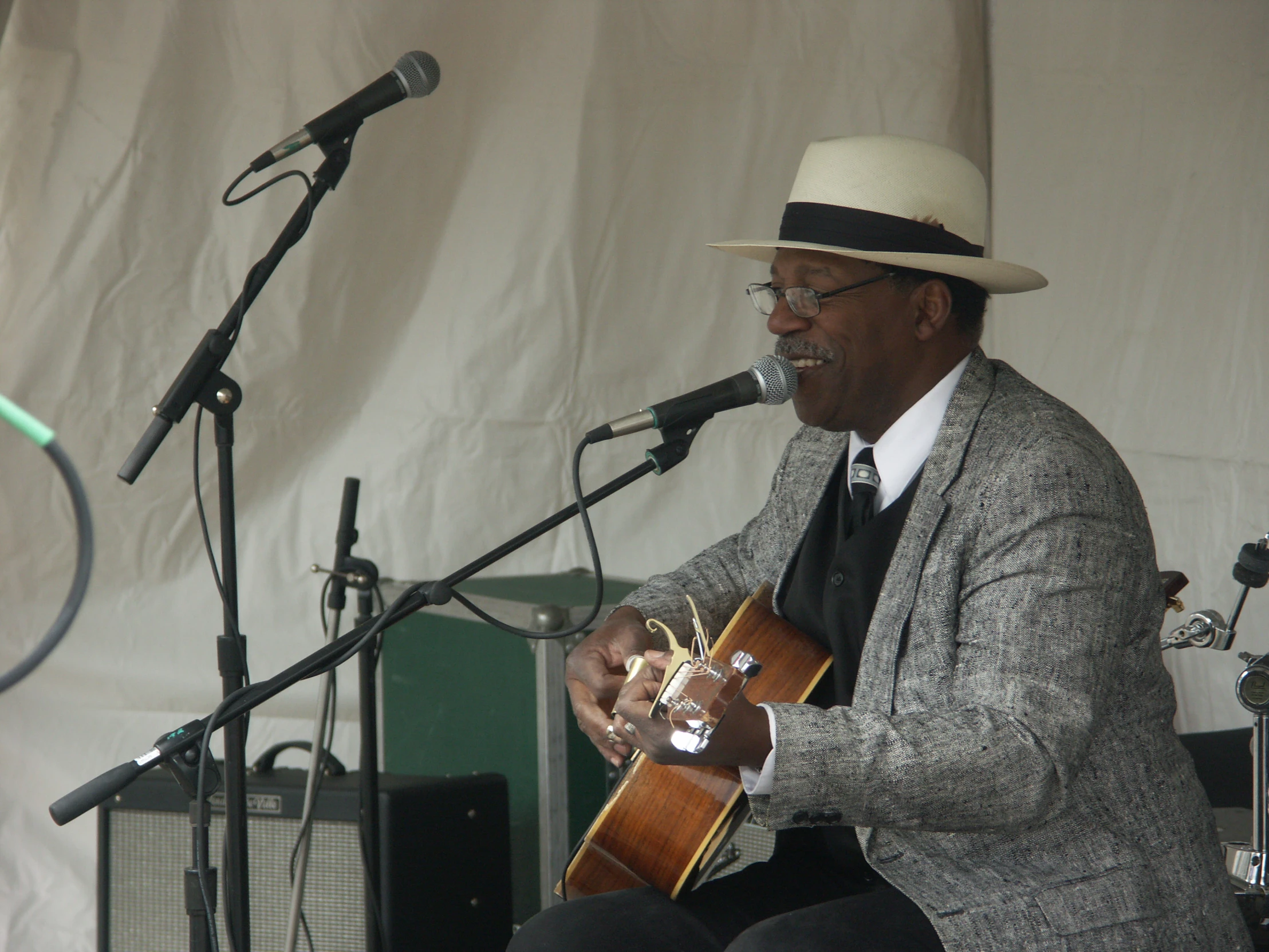 a man in suit playing a guitar while standing in front of microphones
