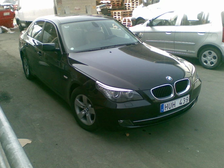 a black bmw parked in an outside lot next to some cars