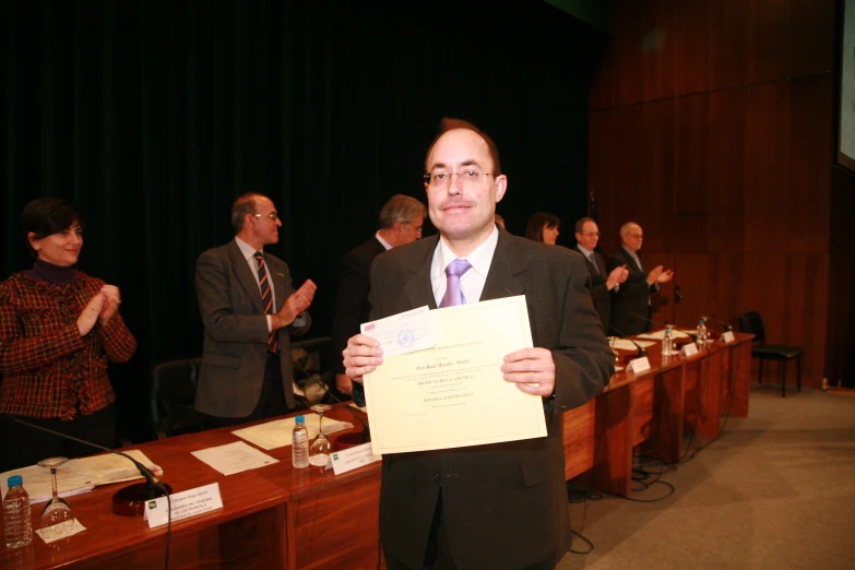 a man in a suit holding a paper near a group of people