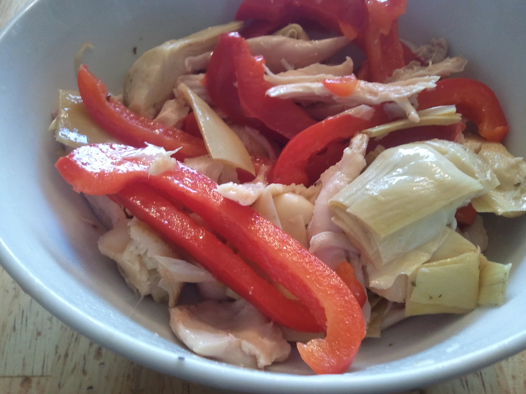 a white bowl filled with chopped veggies and meat