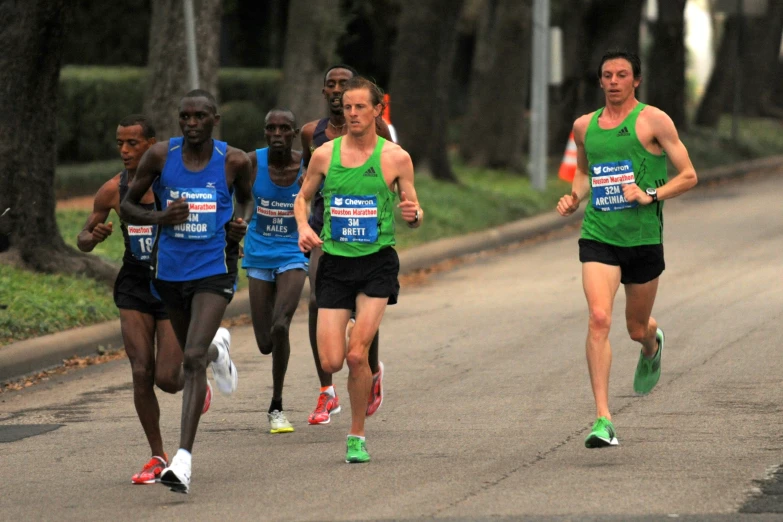 a few men in running outfits racing down the road