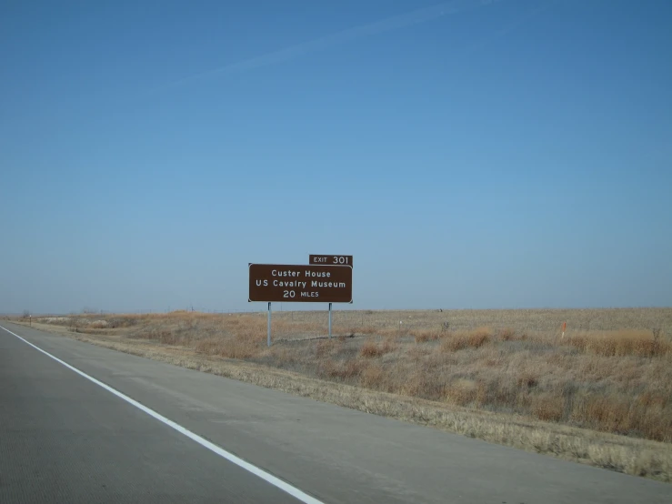 the large brown sign is posted on a highway