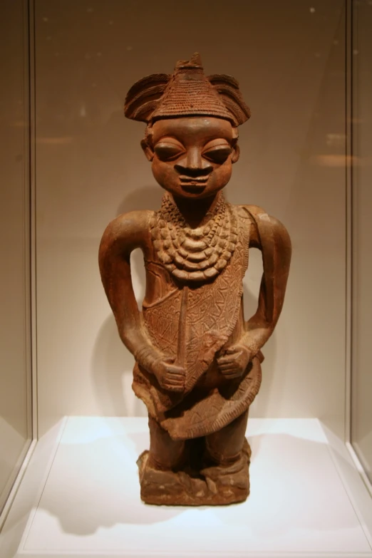 an african statue is displayed in a glass case