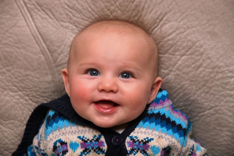 a baby boy in a sweater is smiling for the camera