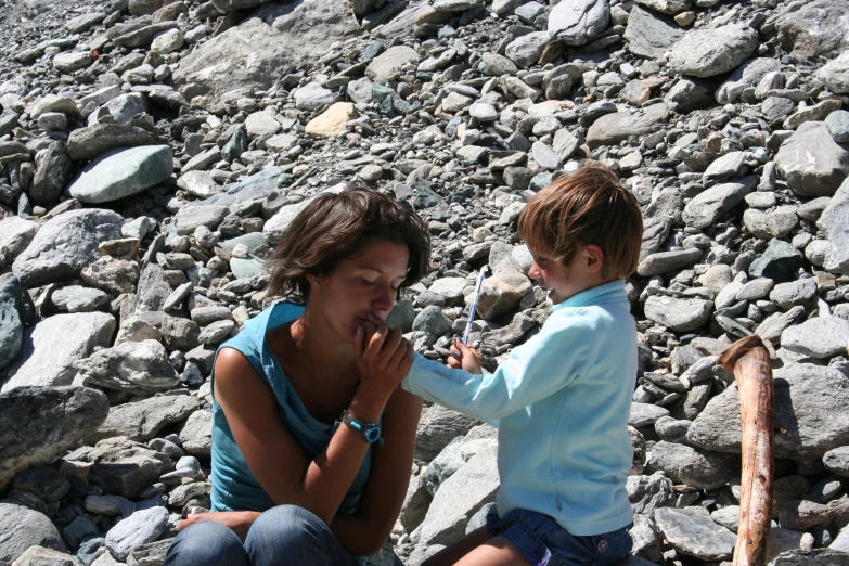 a woman and child sitting on rocks with rocks near her