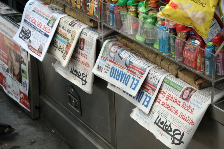 several newspapers are stacked on the shelf in a grocery store