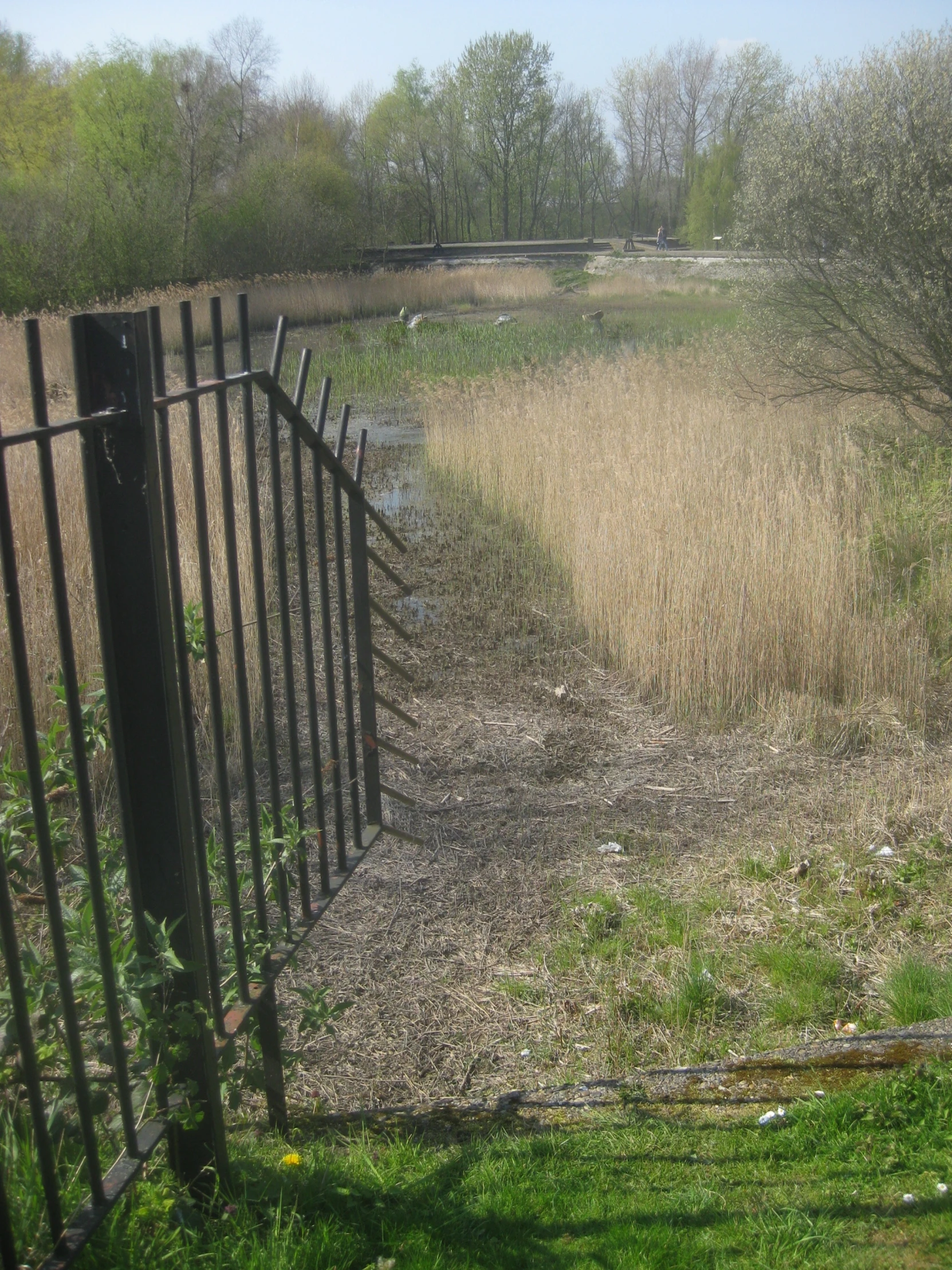 a small fence stands in front of a dry grass area