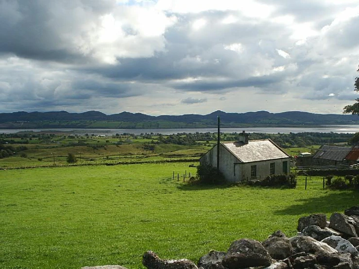 a small church in a grassy field, with a lake in the background