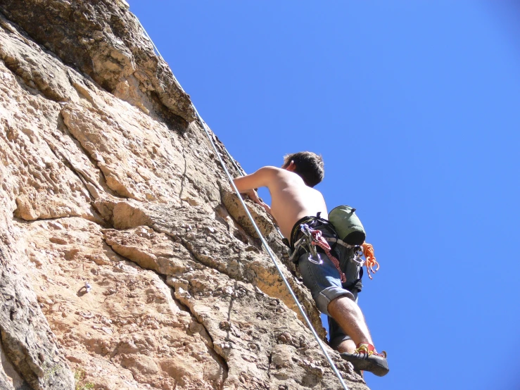 a man climbing up the side of a mountain next to a hiker