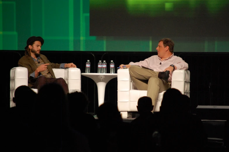 two men sitting in chairs next to each other