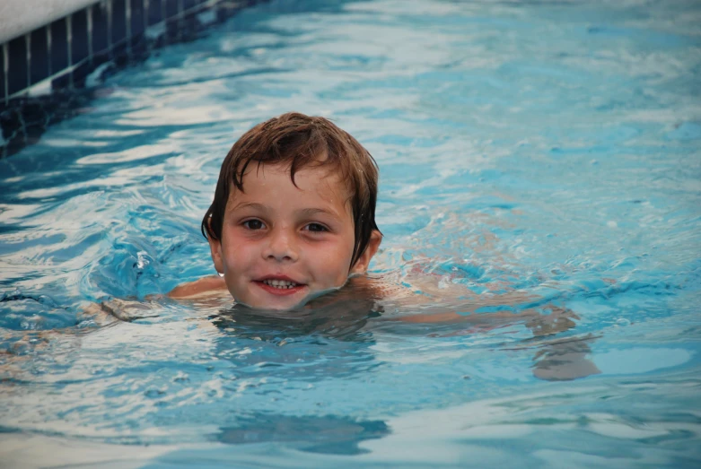 an adorable boy is swimming in the pool