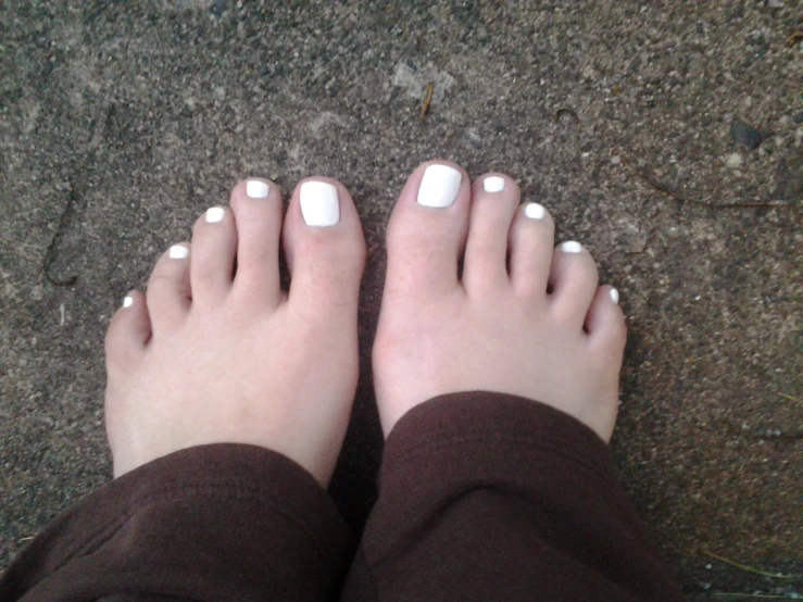 a person's feet with white manicures and brown top