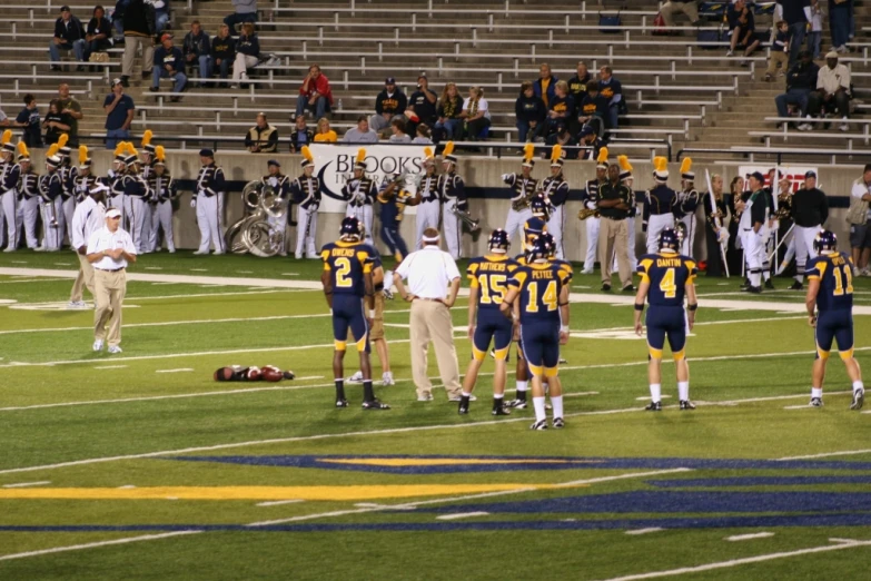 football players and coaches standing in a stadium with referee
