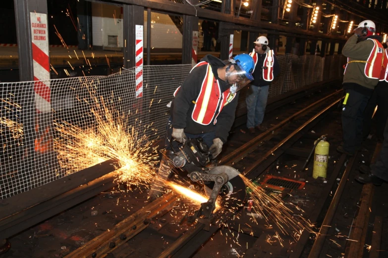 workers work on a train track with metal sparks