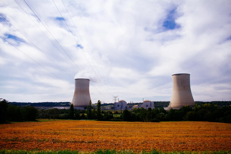 two cooling towers sit in the middle of a field