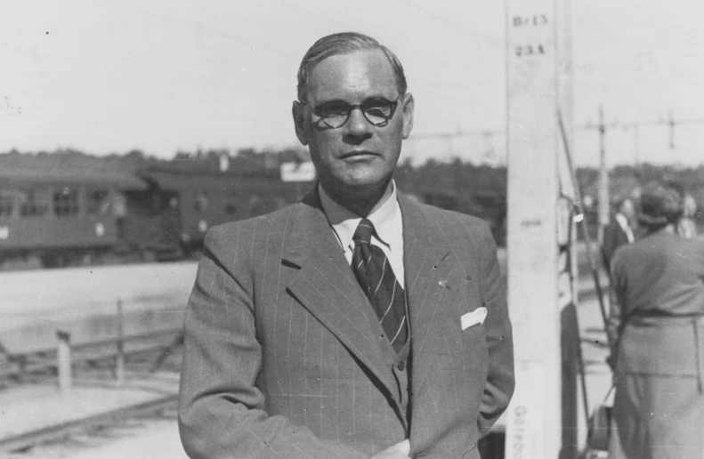 a man in glasses and a suit looks off to the side