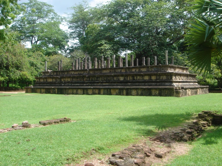 the ruins in a jungle type environment are set within a large green park