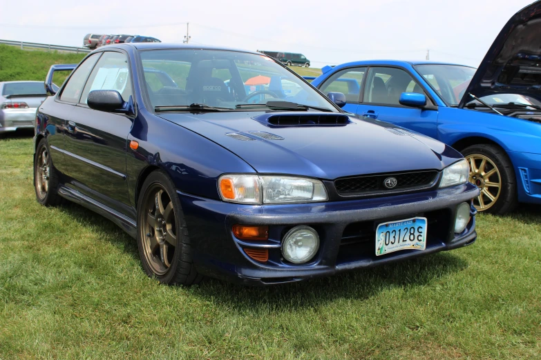 blue toyota corollier car parked near other cars on grassy area