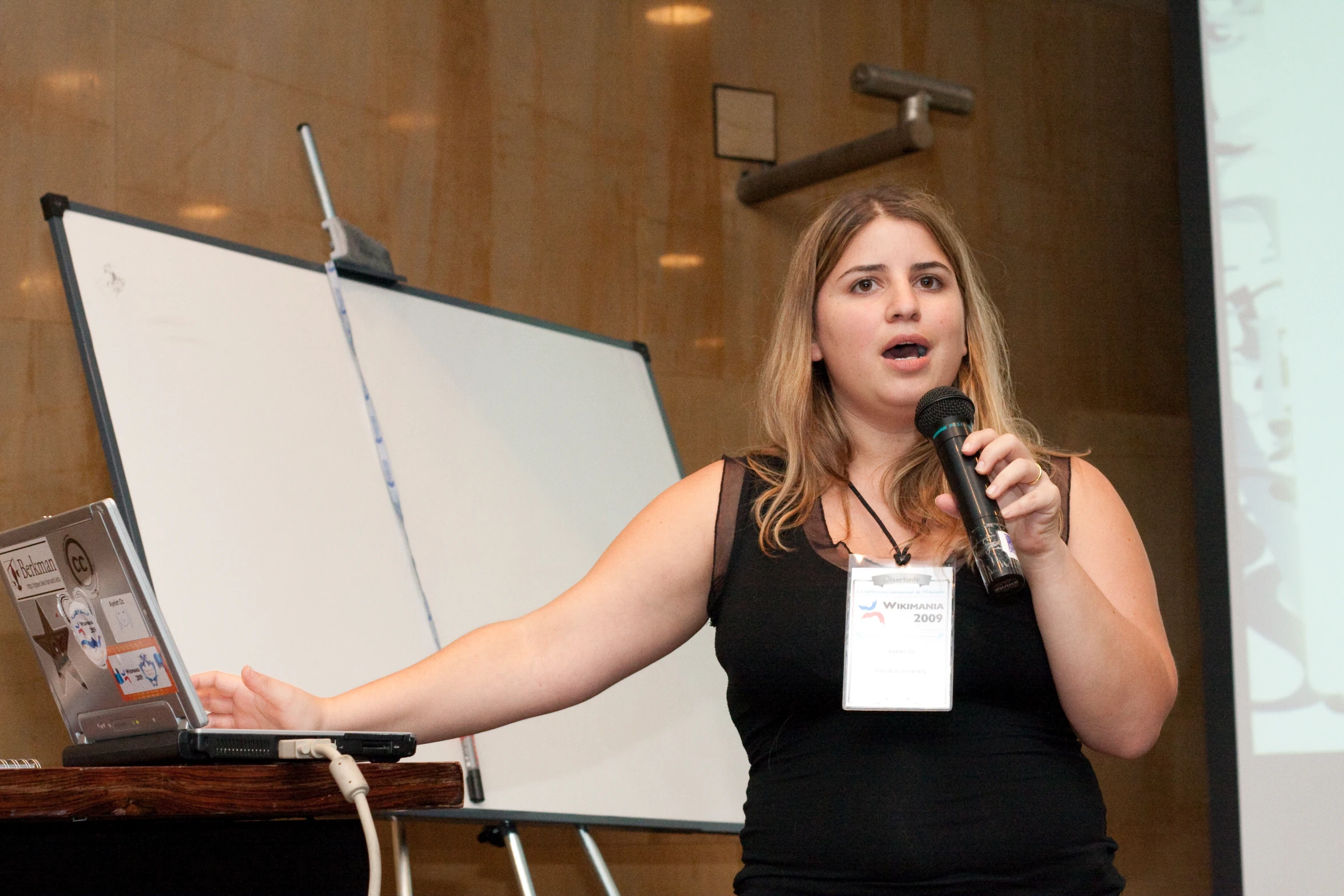 the woman is speaking at the conference as she holds a laptop