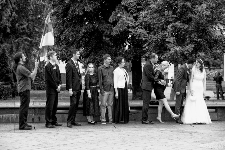 a group of people stand around in front of some trees